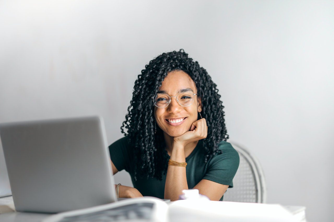 Image of a woman on a laptop smiling at the camera