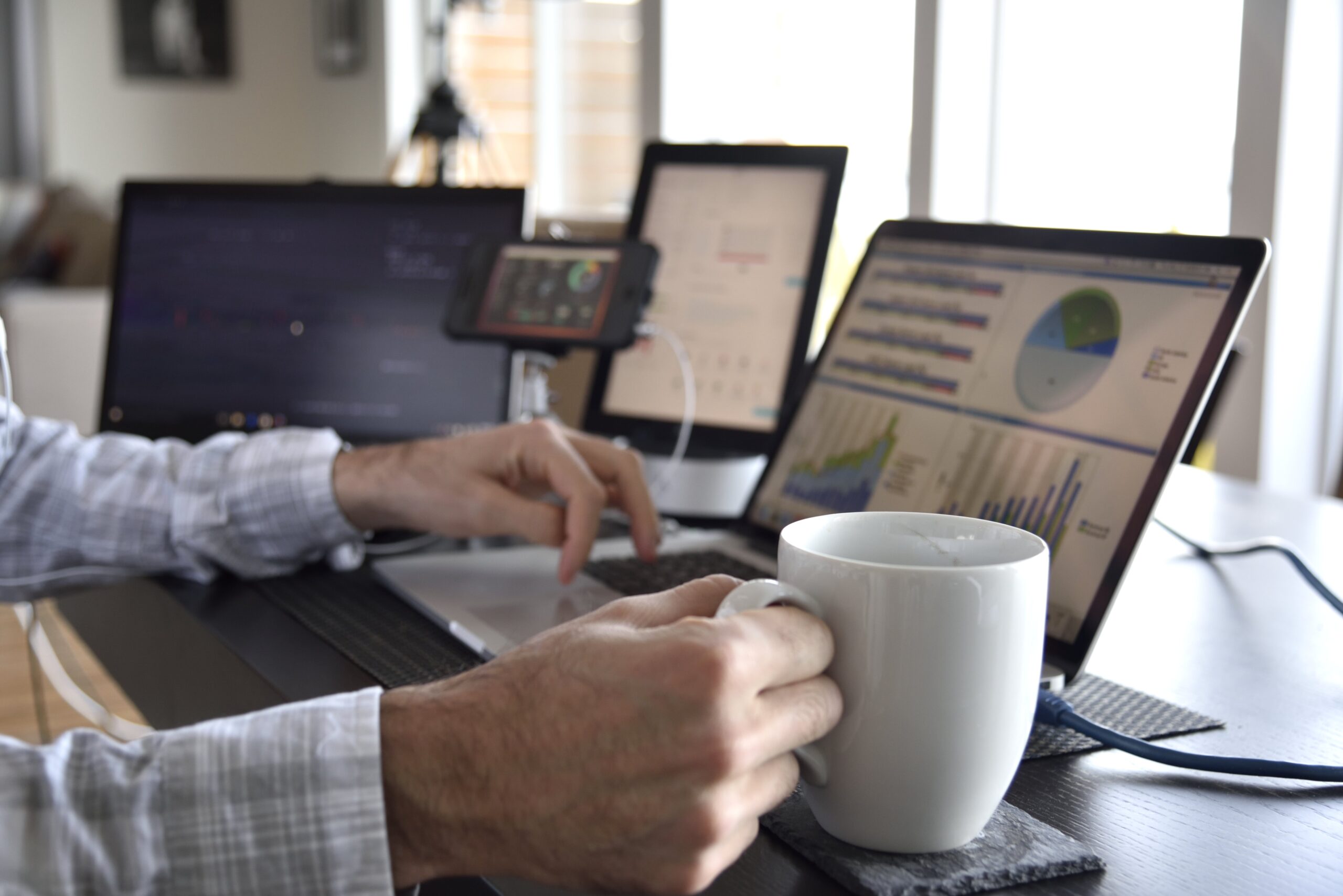 image of man at desk on laptop with cup of coffee in hand