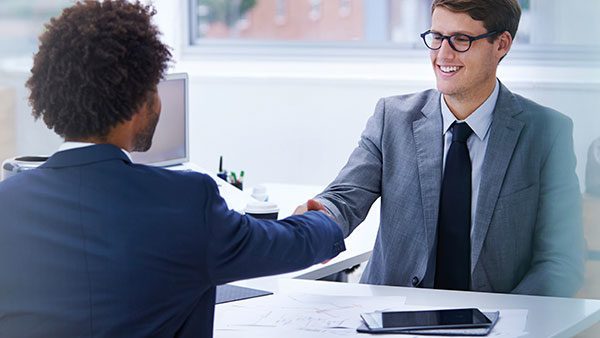 Image of two business people shaking hands seated in office