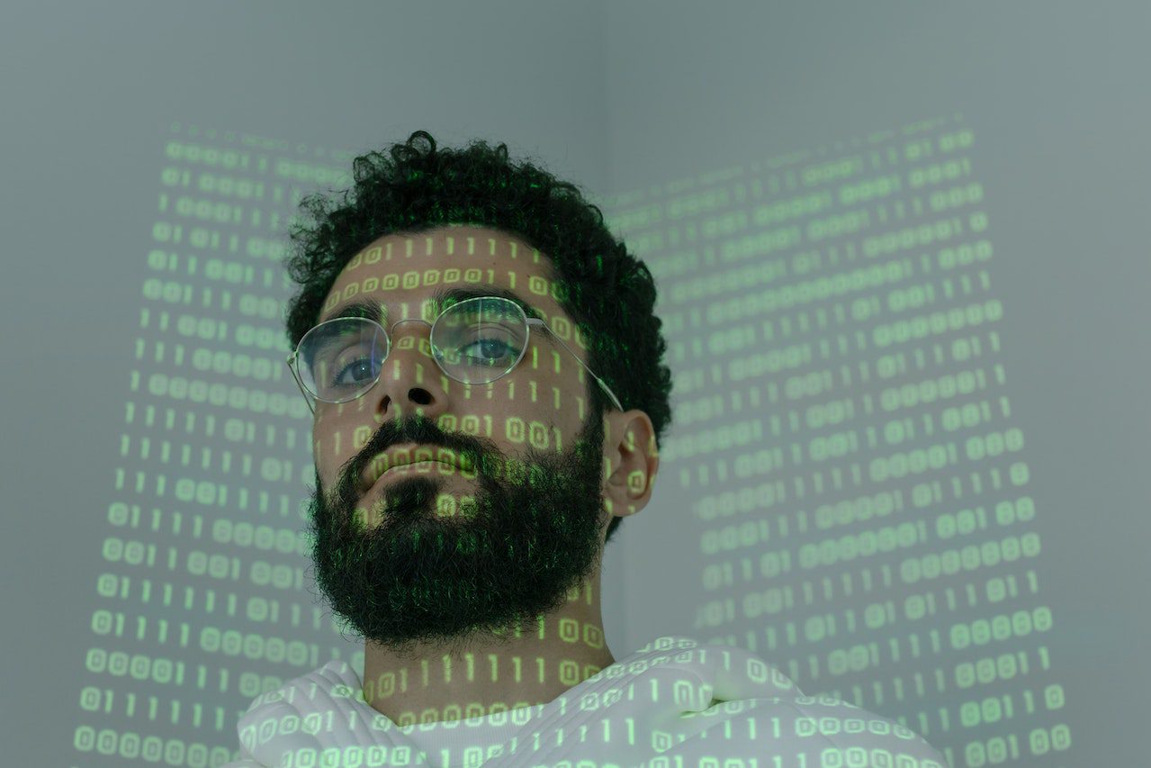 Image of man with green code projected on him and wall behind