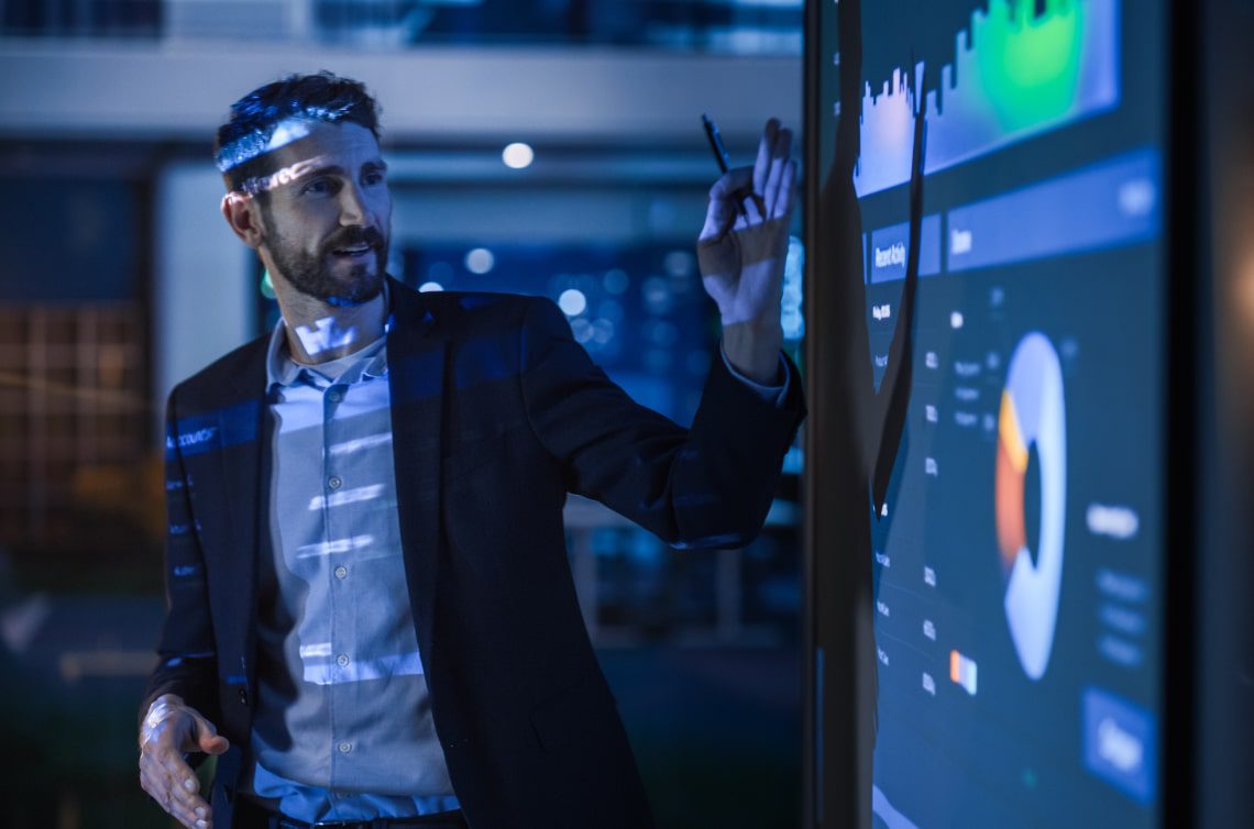 Image of a man presenting a dashboard on projector in the dark